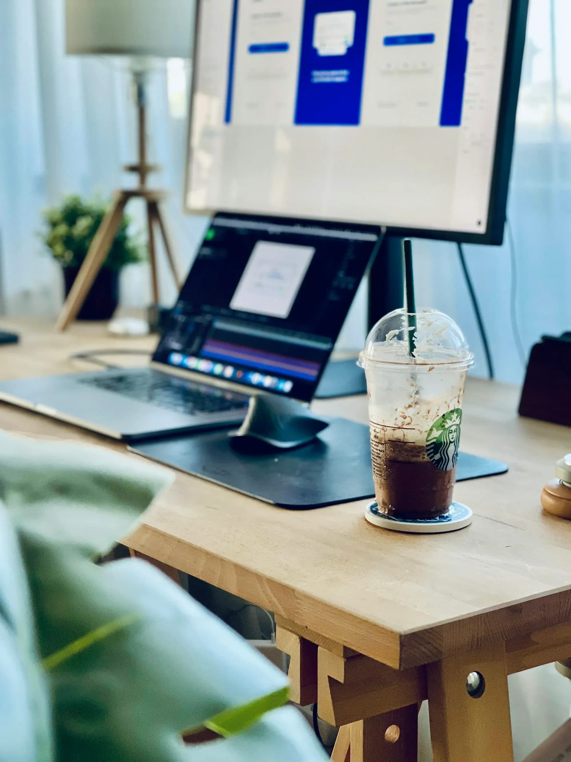 Schreibtisch mit Monitor und Laptop, auf dem Bildschirm eine Website